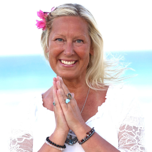 Angelic Jeanette A woman dressed in white with a flower in her blonde hair greeting into the camera.