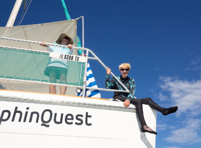Two women, one standing and one sitting, on a catamaran.