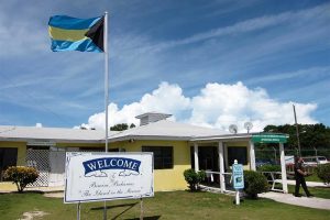 Building with Bahamian flag in front and person walking away.