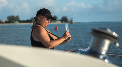 woman standing on a boat taking photos with a mobile phone.