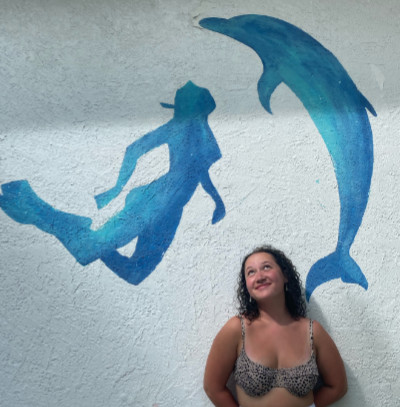 woman standing in front of a mural showing a woman and a dolphin