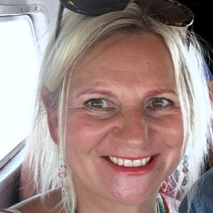 Nicky Marchant Close up shot of a woman smiling into the camera with sunglasses in her hair.