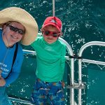 Woman and boy standing on boat looking up